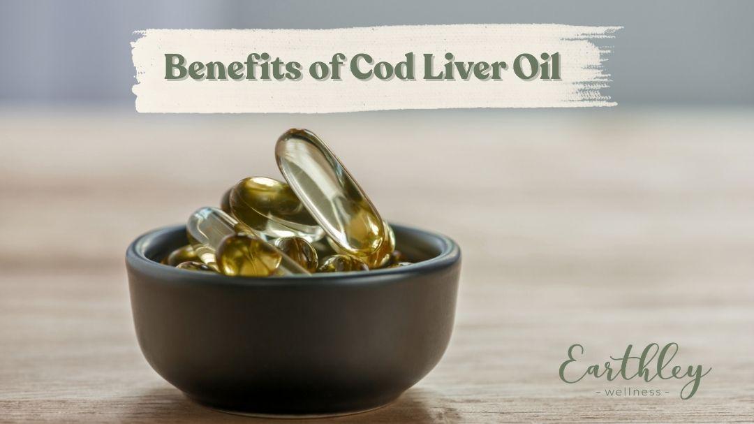Golden cod liver oil softgel capsules overflowing a small black bowl on a wooden surface.