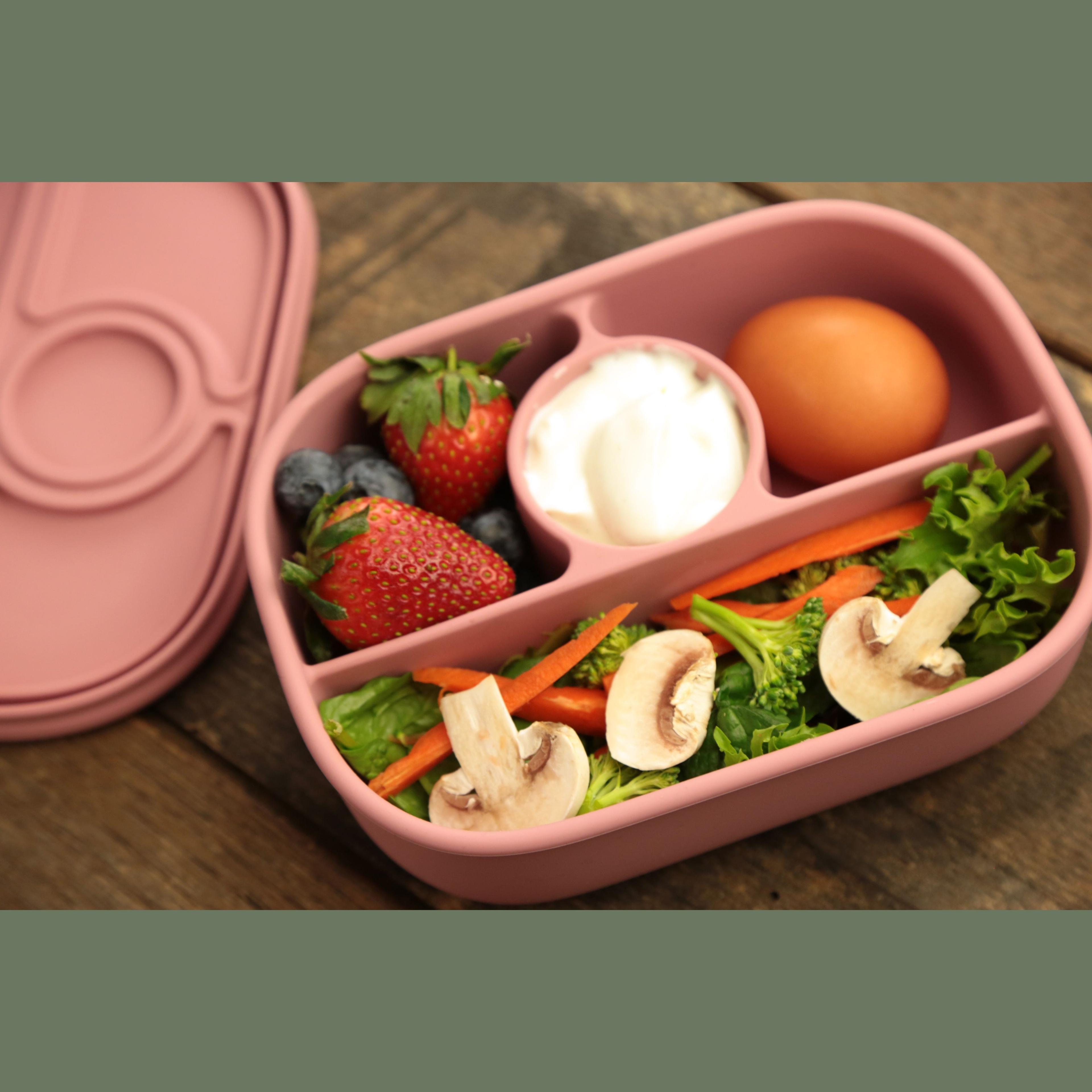 Calla and Friends silicone bento box in dusty rose pink color opened showing compartments filled with fresh salad, mushrooms, broccoli, carrots, hard boiled egg, yogurt dip, strawberries and blueberries