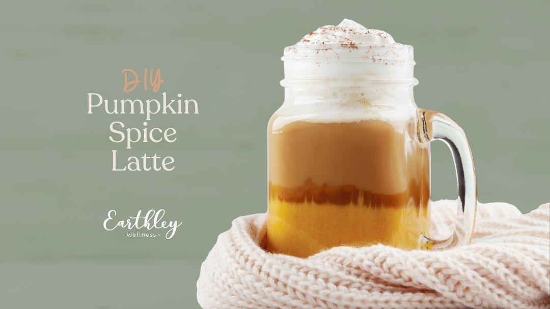 DIY pumpkin spice latte in a glass mug with whipped cream, wrapped in a cozy knit scarf