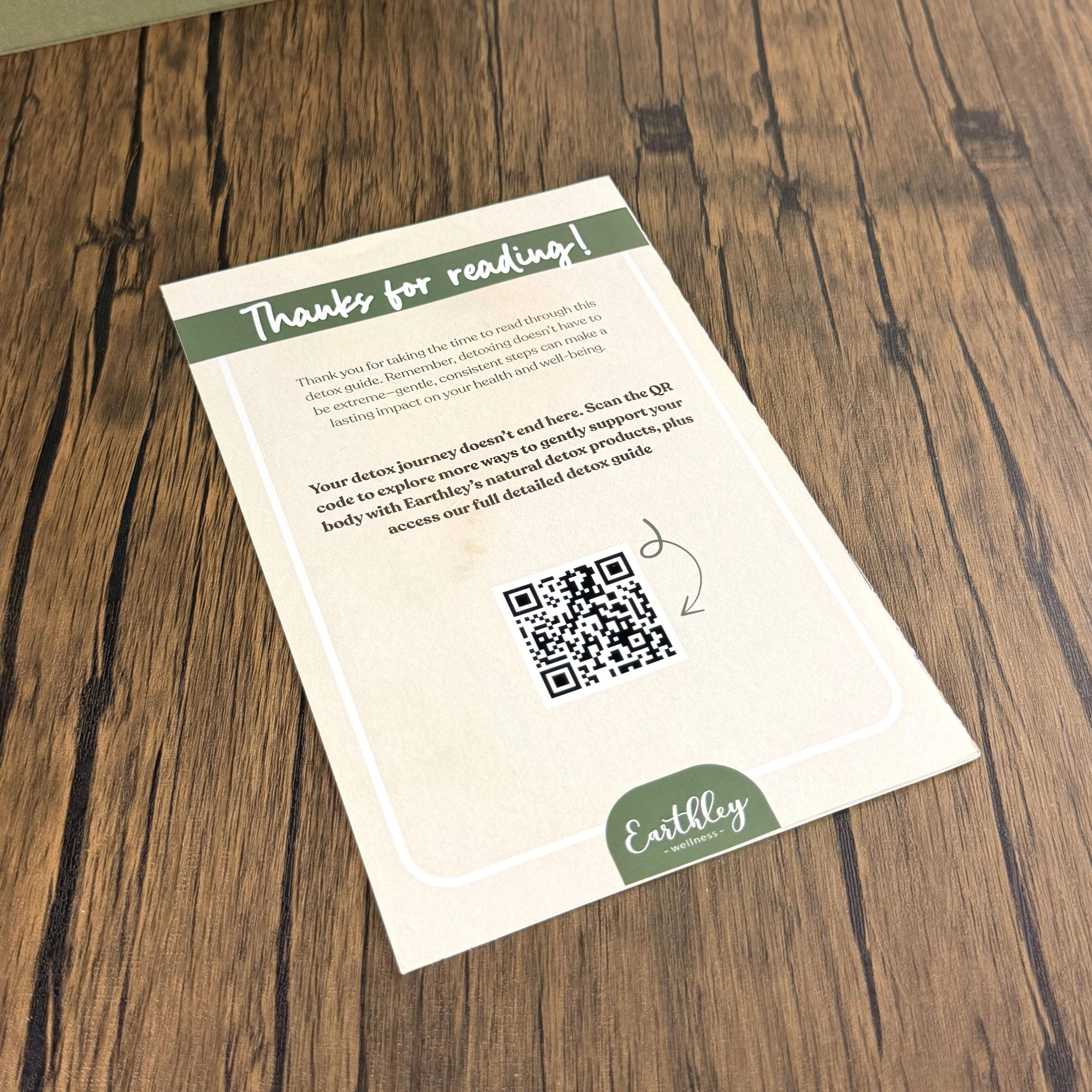 Earthley Wellness detox guide back card with QR code on wood surface