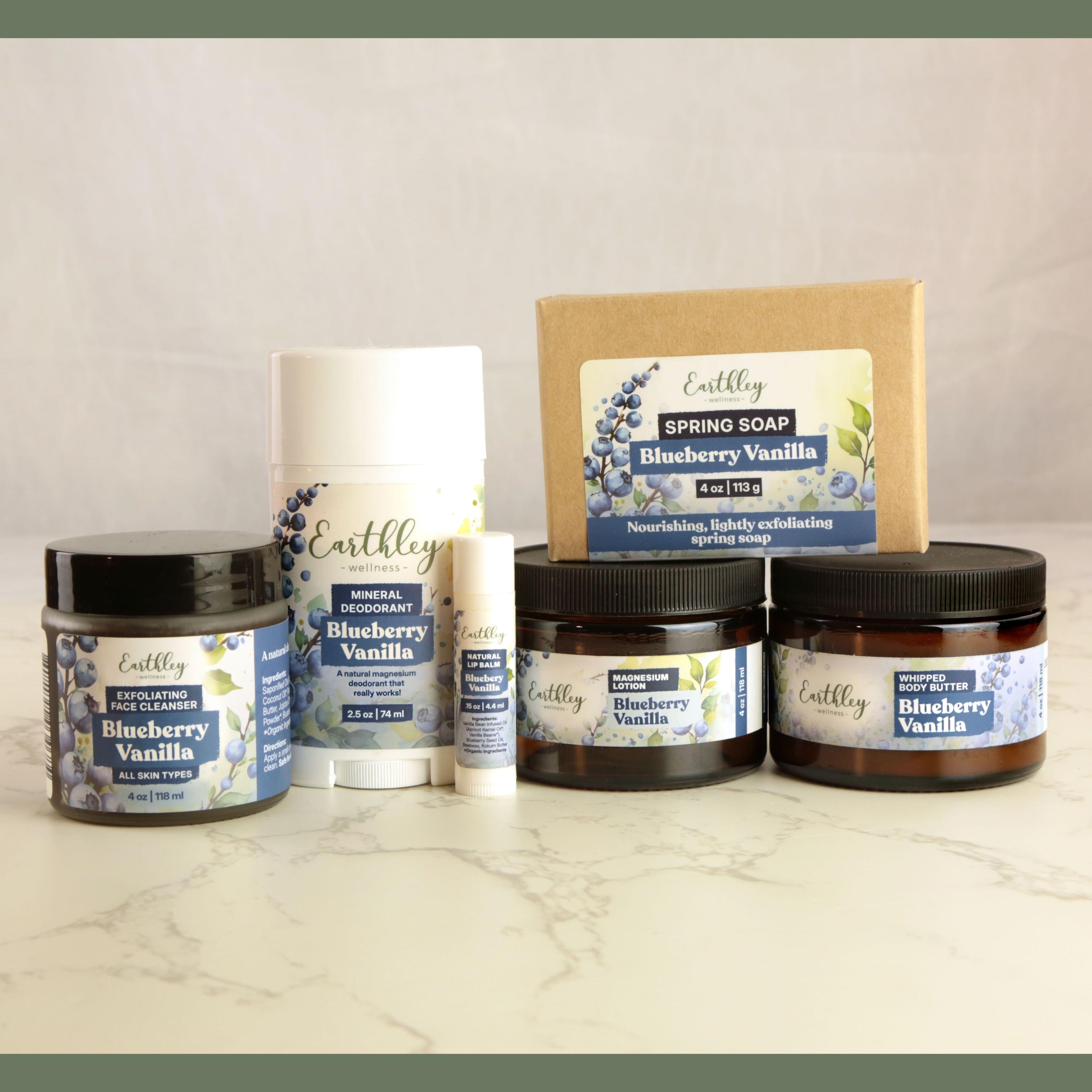 Earthley Blueberry Vanilla skincare collection including face cleanser, deodorant, soap, lip balm, magnesium lotion, and body butter
