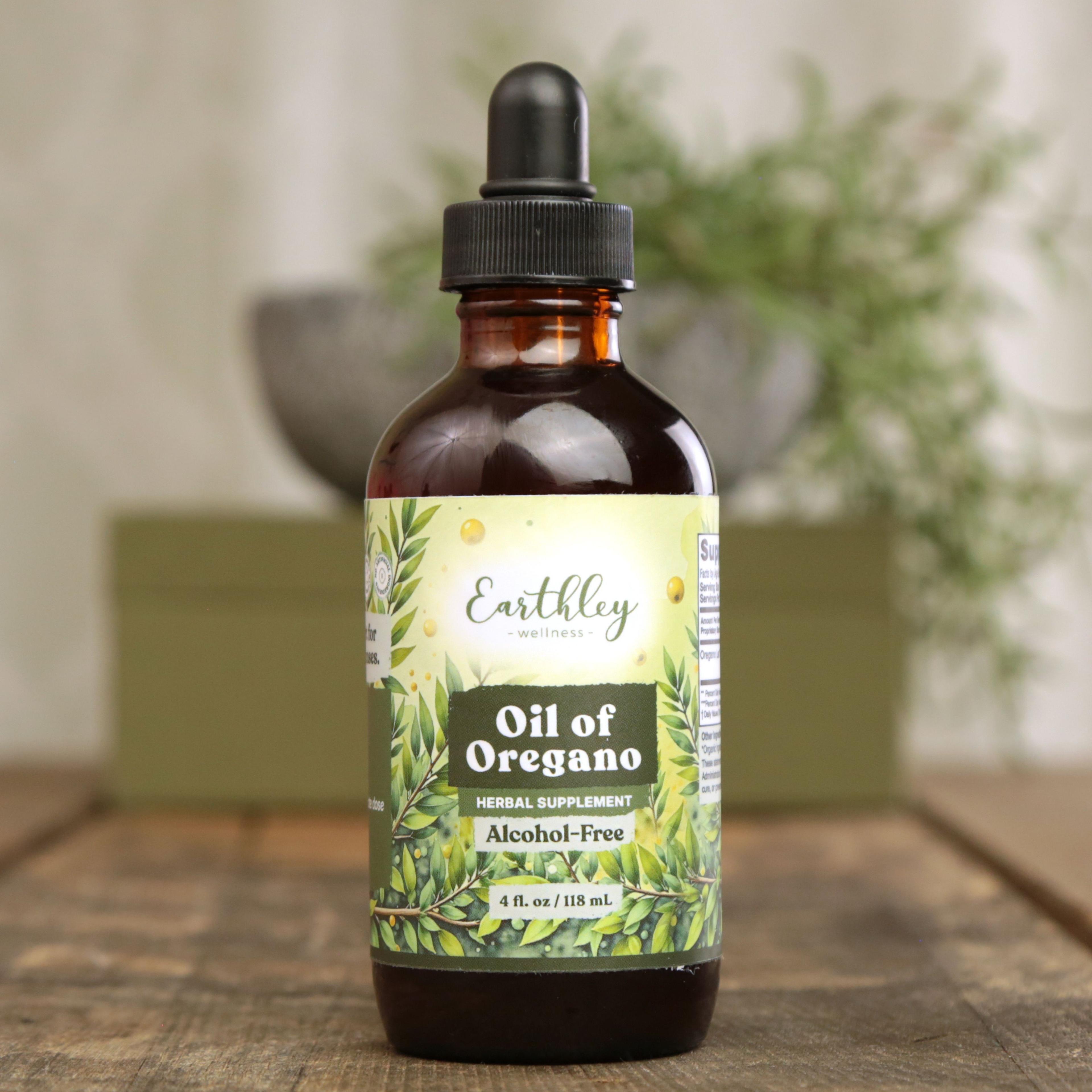 Earthley Oil of Oregano 4 oz amber dropper bottle with green oregano leaf label, labeled as Herbal Supplement Alcohol-Free, on wooden surface with plants in background