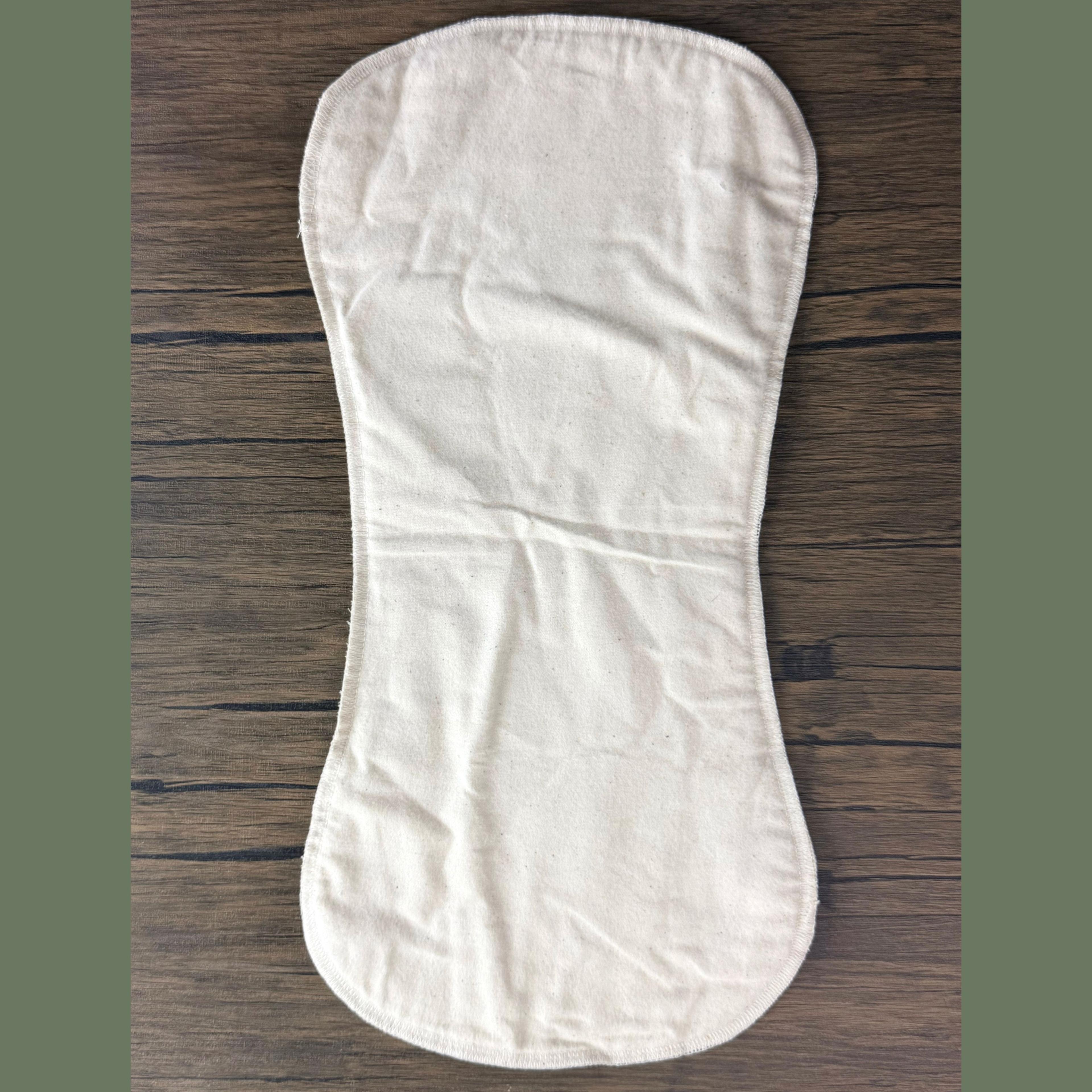 Reusable cloth menstrual pad in natural white cotton on wood surface