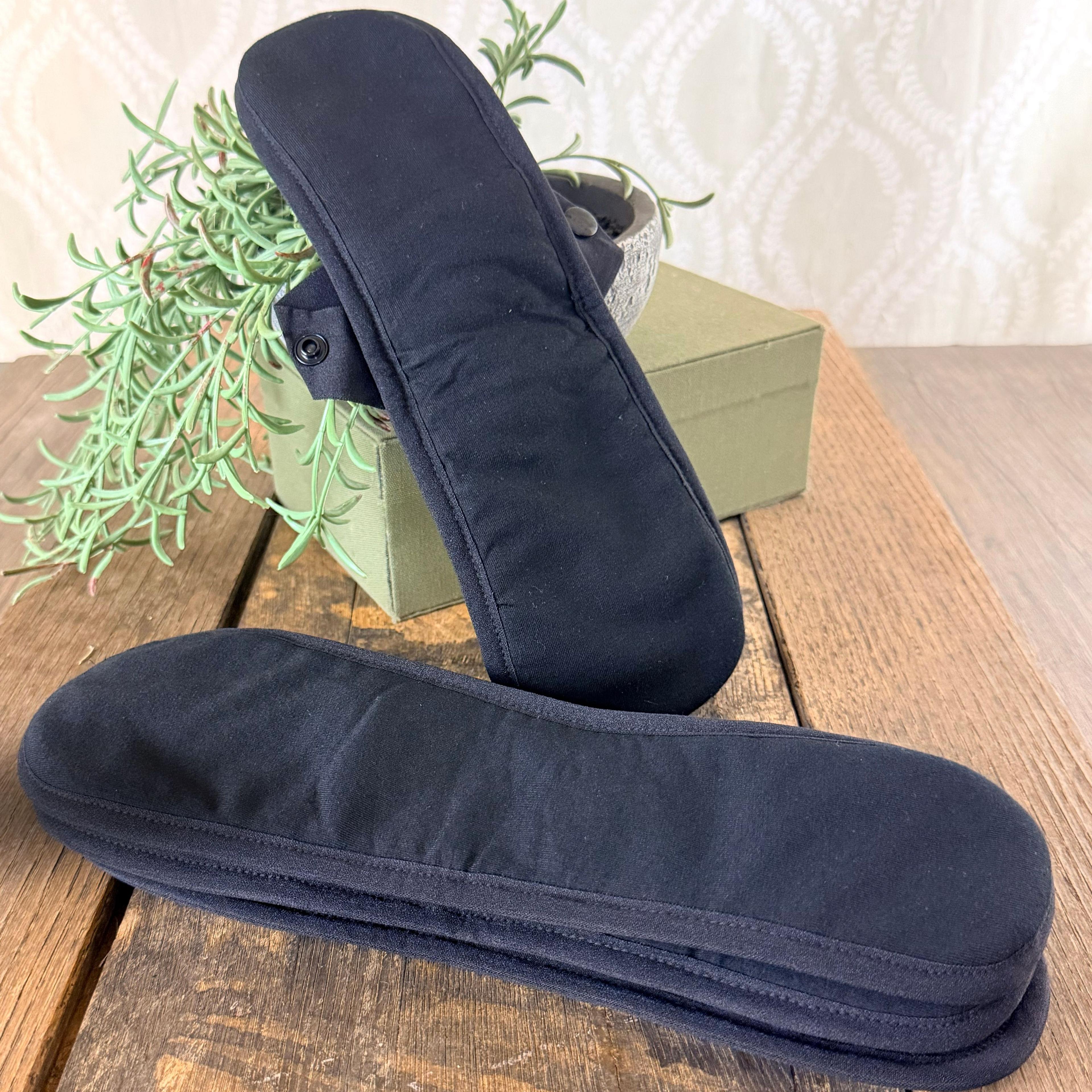 Period Pads leaned against a plant setting. Reusable Cloth Menstrual Pads