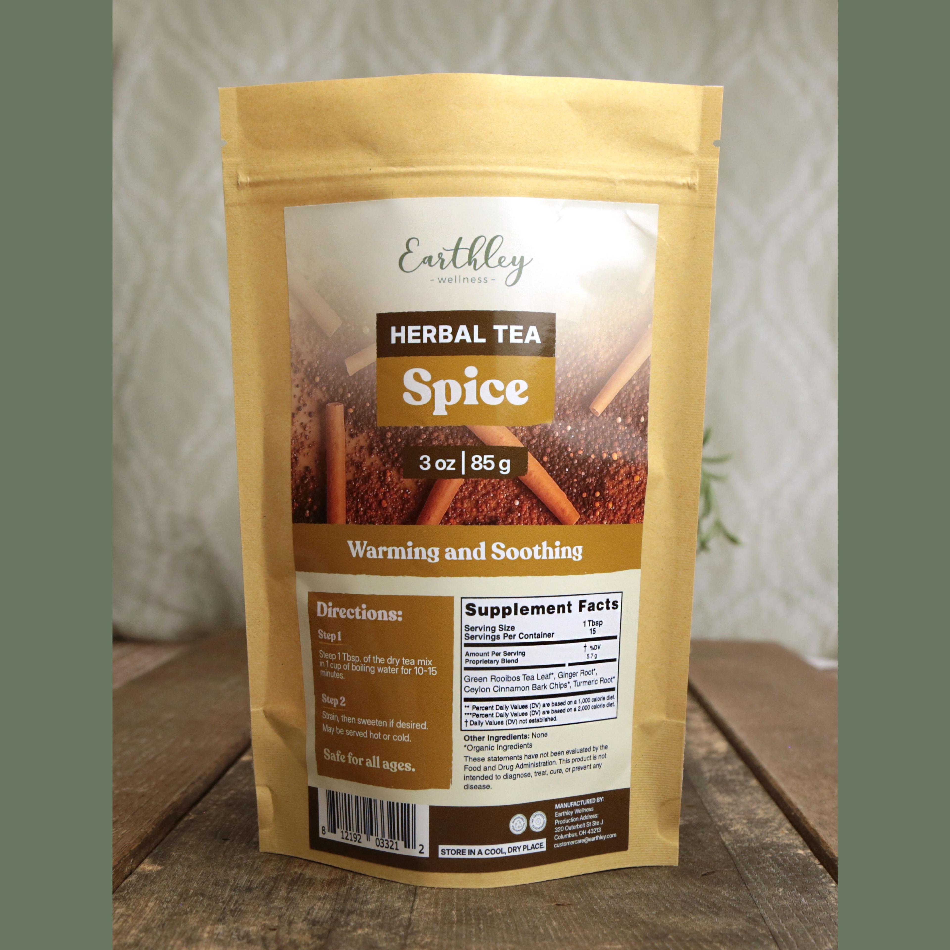 Earthley Wellness Spice Herbal Tea package in kraft pouch with cinnamon sticks and warming spices on wooden surface