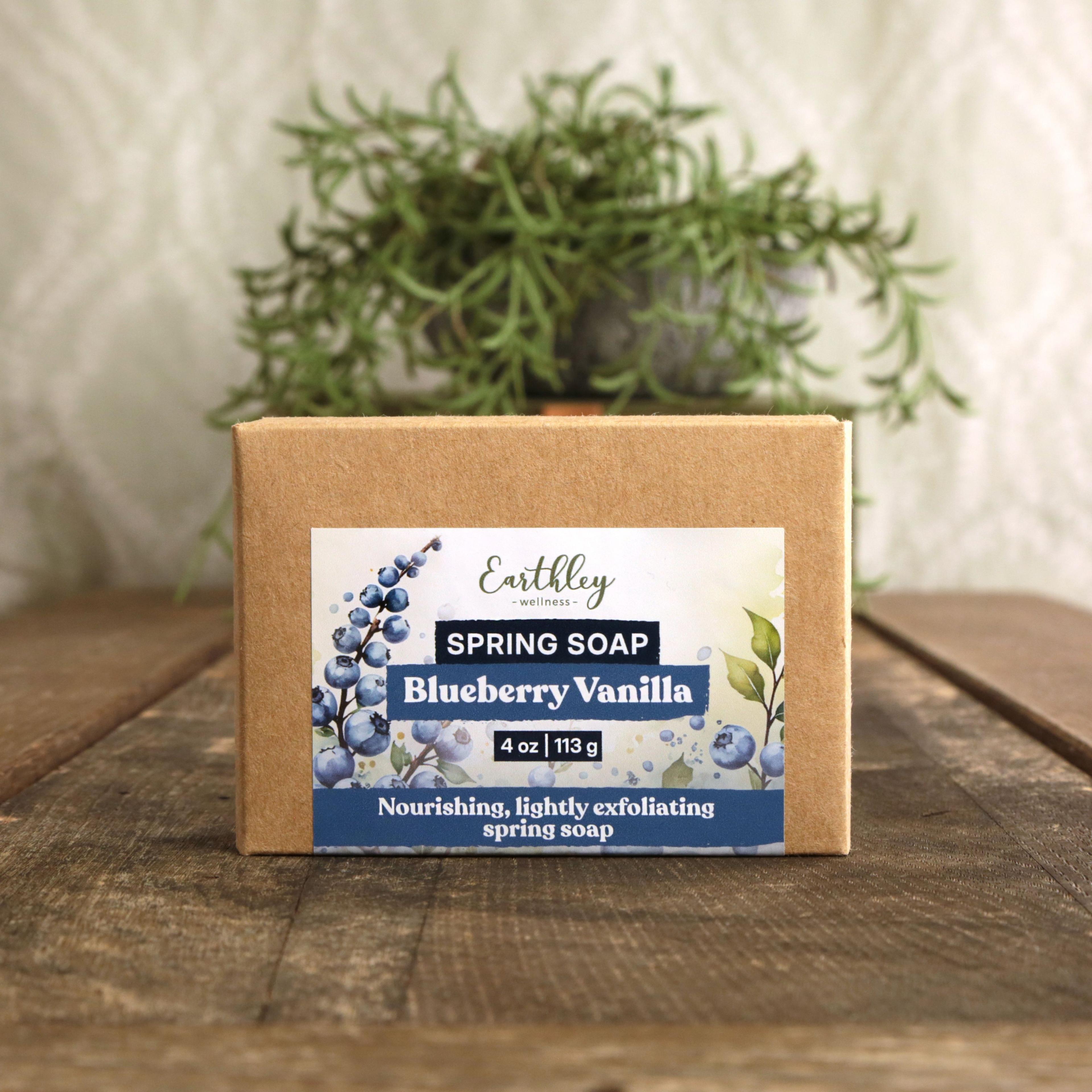 Earthley Spring Soap Blueberry Vanilla 4 oz in kraft paper box with purple blueberry botanical label on wooden surface