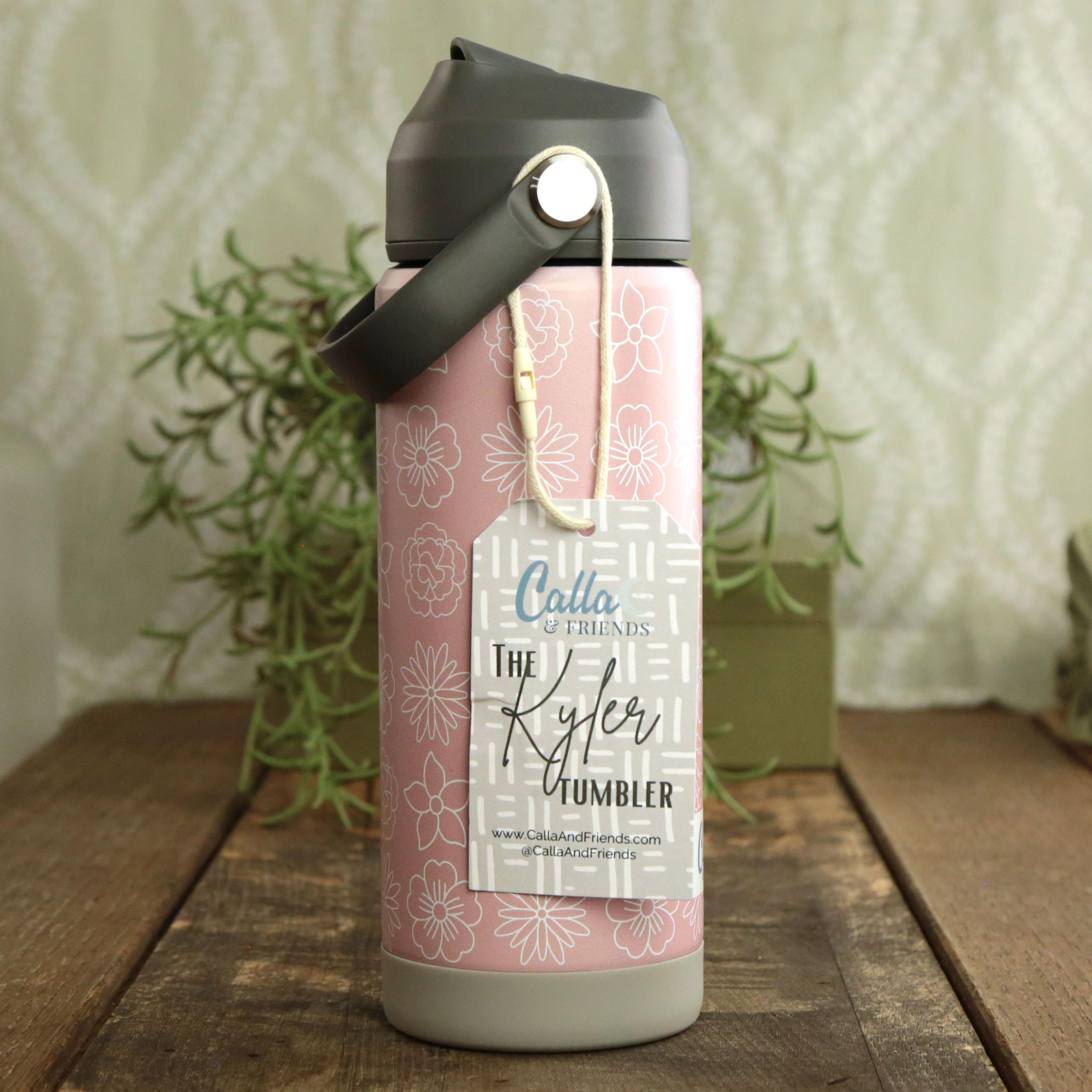 Calla and Friends Kyler Tumbler stainless steel water bottle in dusty pink with white floral pattern gray flip-top lid and cotton carry strap on rustic wood with rosemary