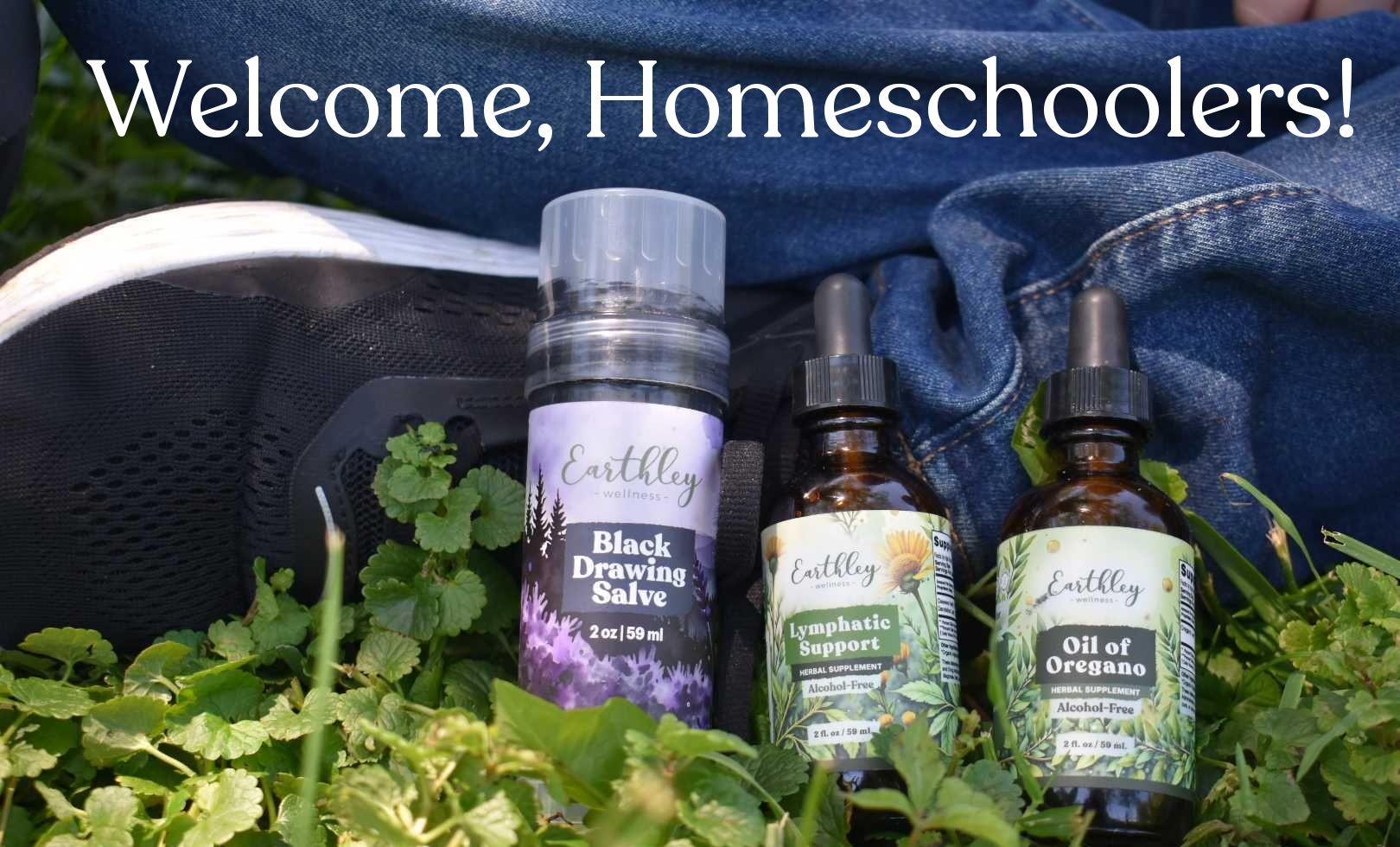 Earthley Wellness Black Drawing Salve, Lymphatic Support, and Oil of Oregano amid green herbs