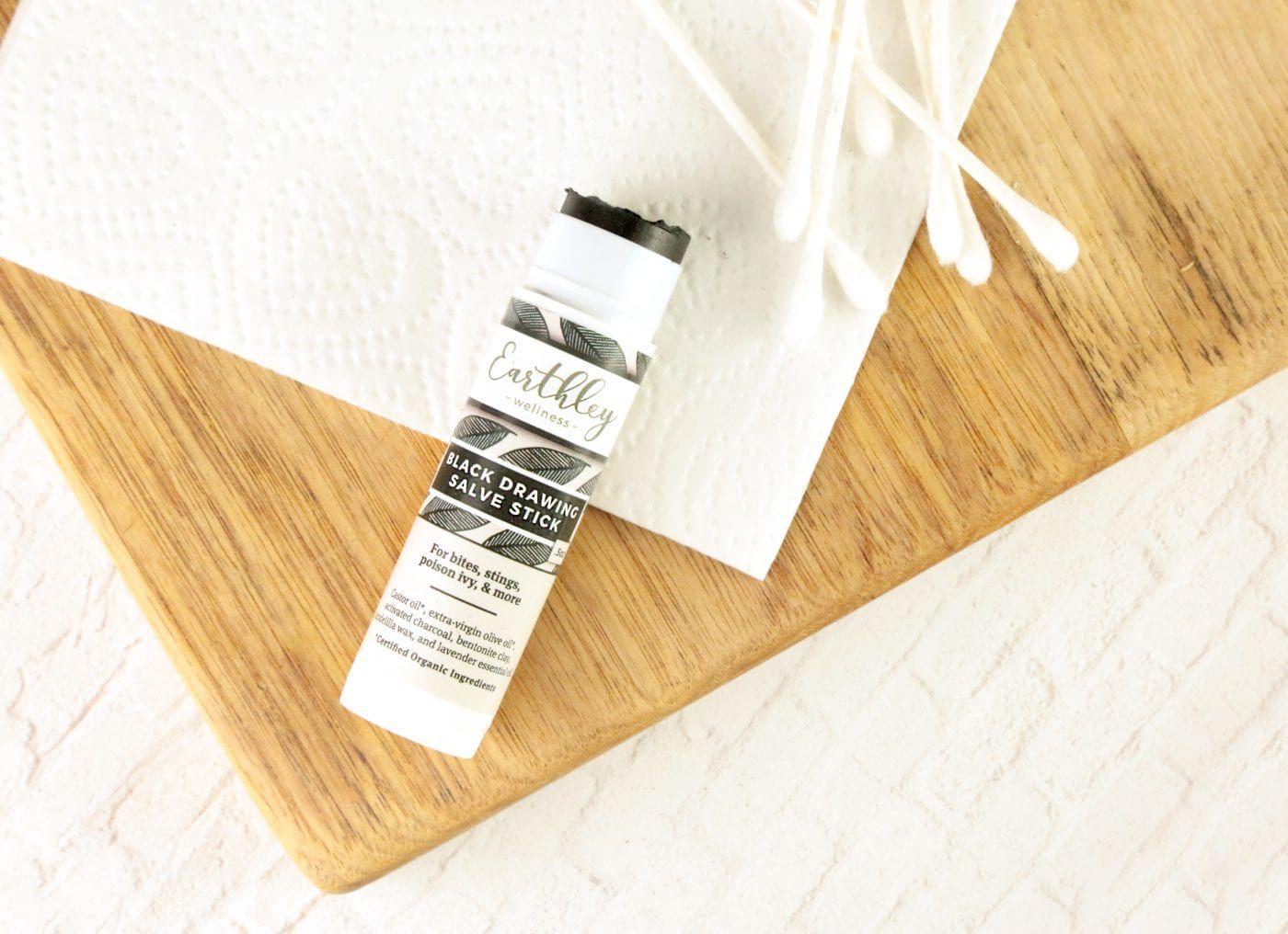 Black Drawing Salve Stick on wood cutting board with cotton swabs for bites and stings