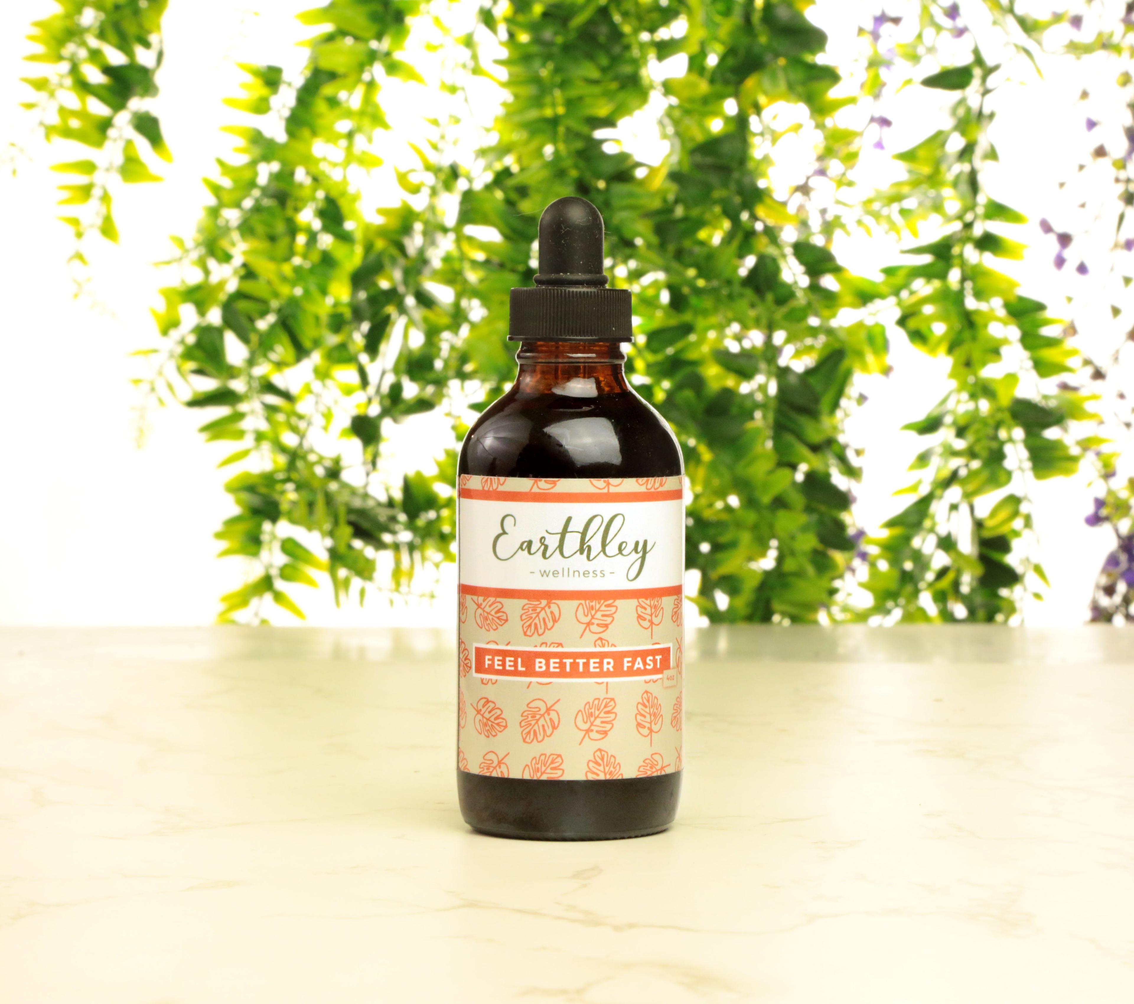 Earthley product display with fresh green leaves and small purple lavender flowers across top portion against white background with gray lower section partially cropped promotional image