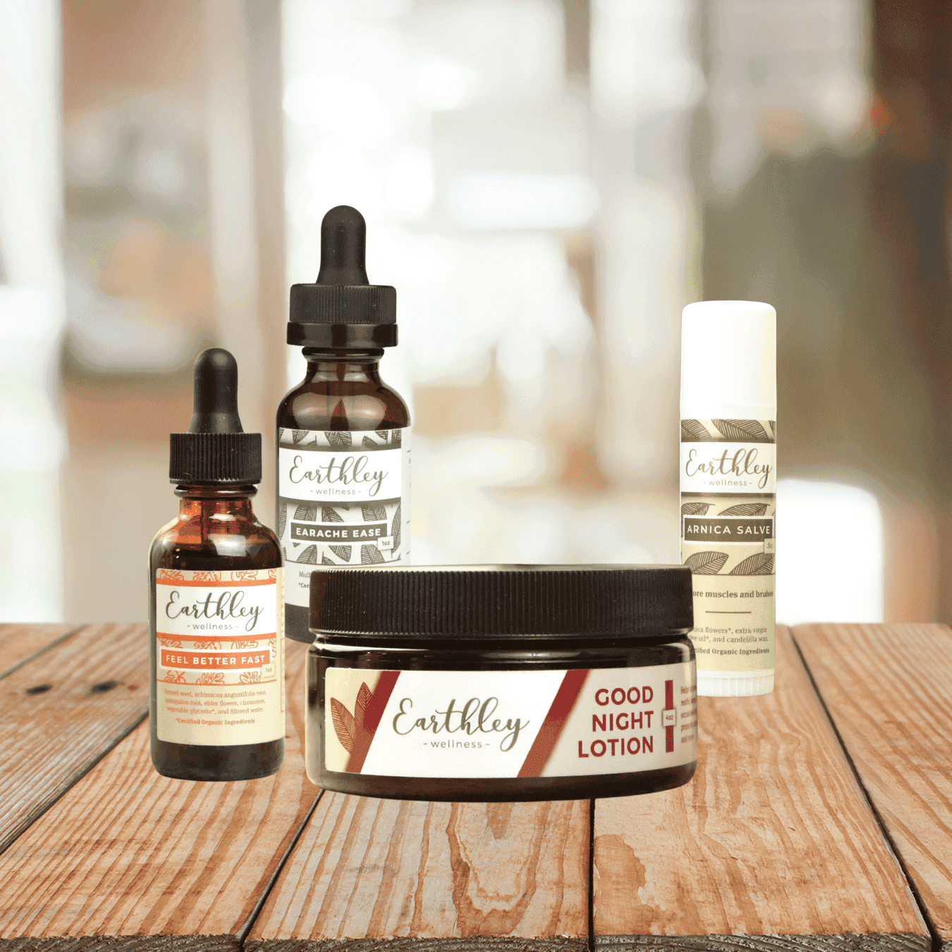 Earthley Chiropractic Wholesaler Bundle featuring amber glass dropper bottles with coral red leaf labels and amber Good Night Lotion jar with black lid white Arnica Salve tube arranged on rustic wooden surface
