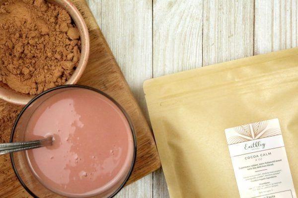 Cocoa Calm bag with bowl of cocoa powder and glass of chocolate drink on wooden board
