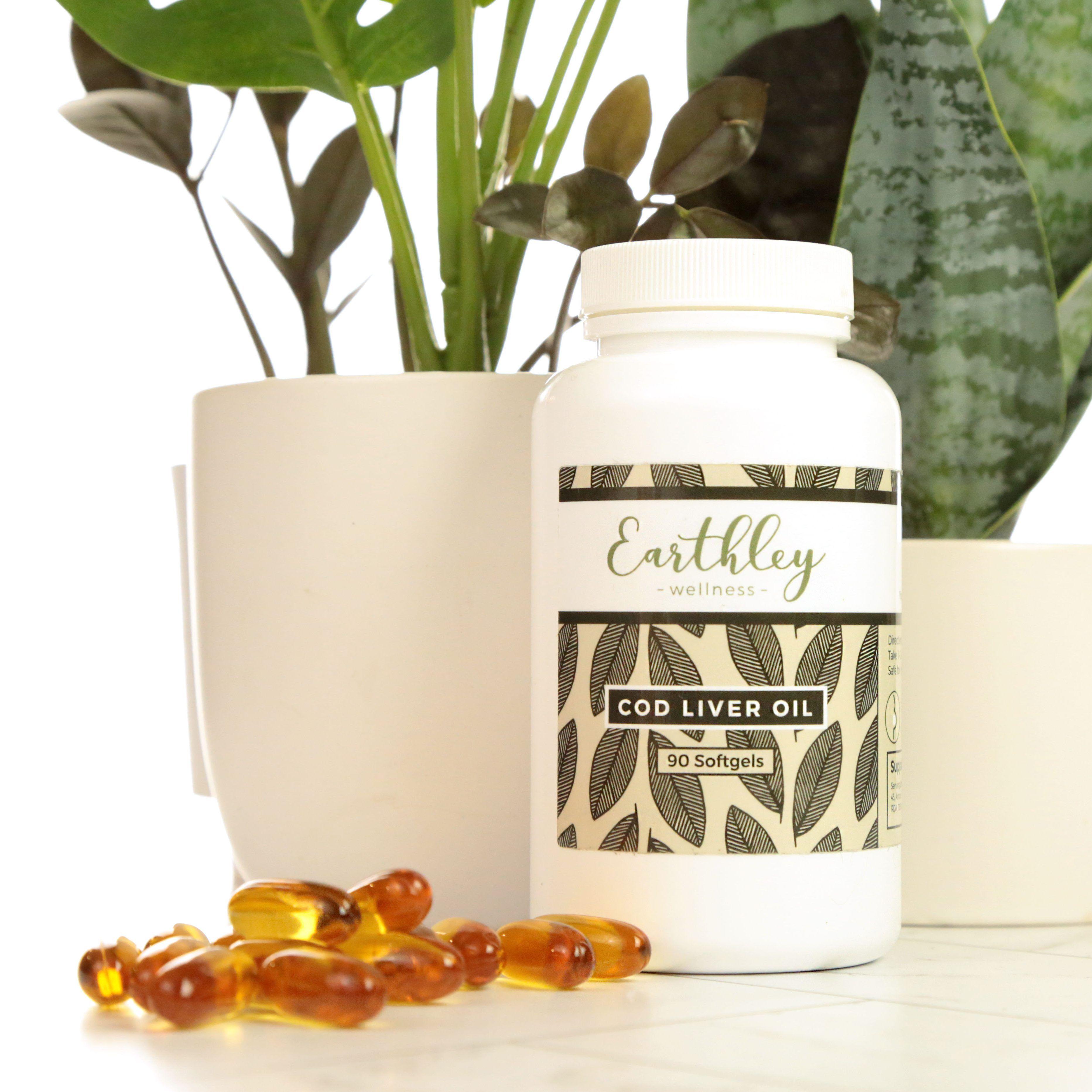 Cod Liver Oil bottle with amber softgels scattered in front and green houseplants behind