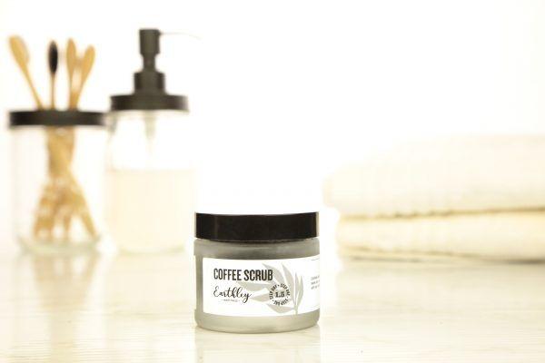 Coffee Scrub jar in bathroom setting with soap dispenser and folded white towels