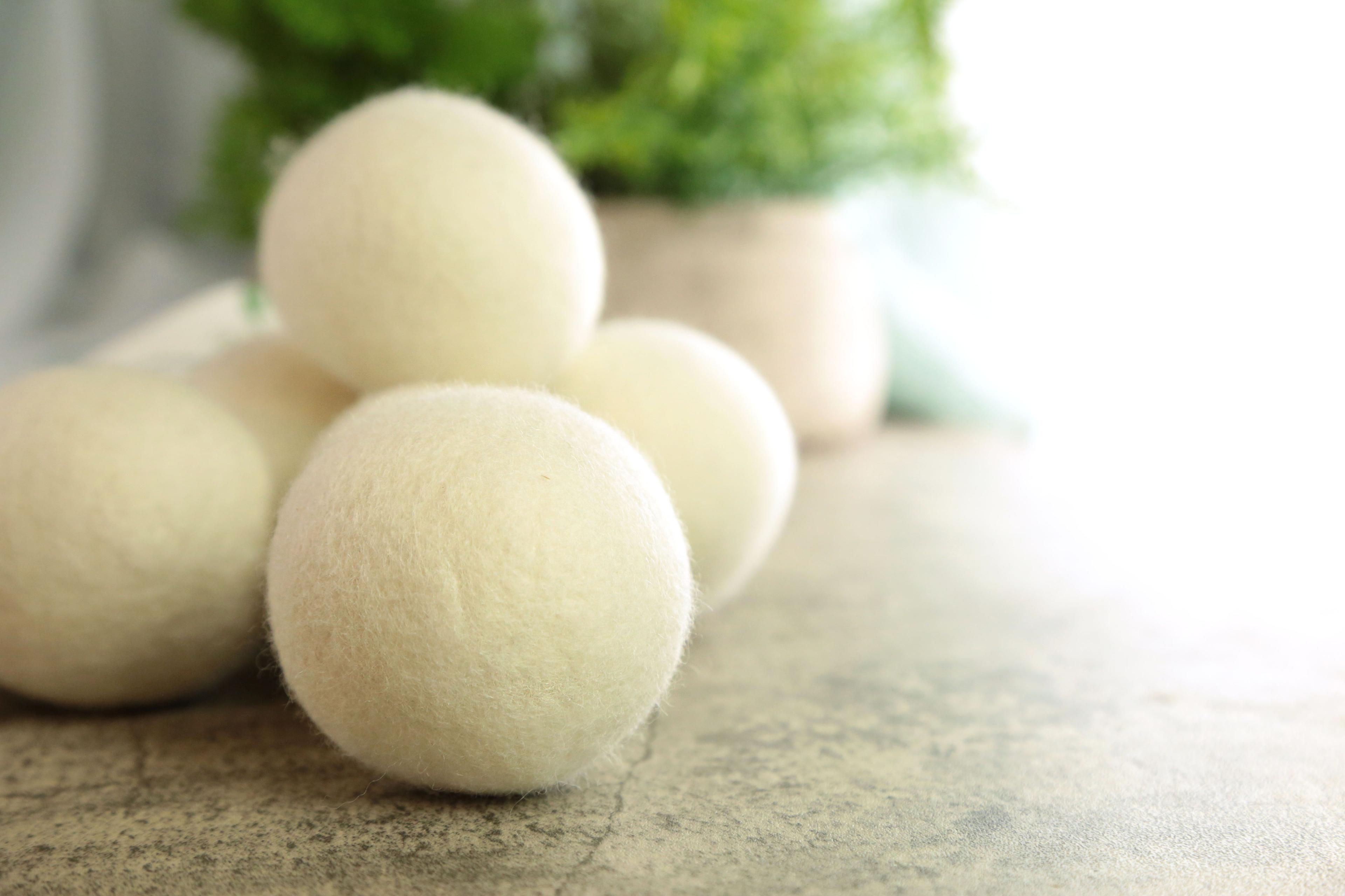 Earthley Wool Dryer Balls pair showing natural off-white felted wool texture close-up on marble surface