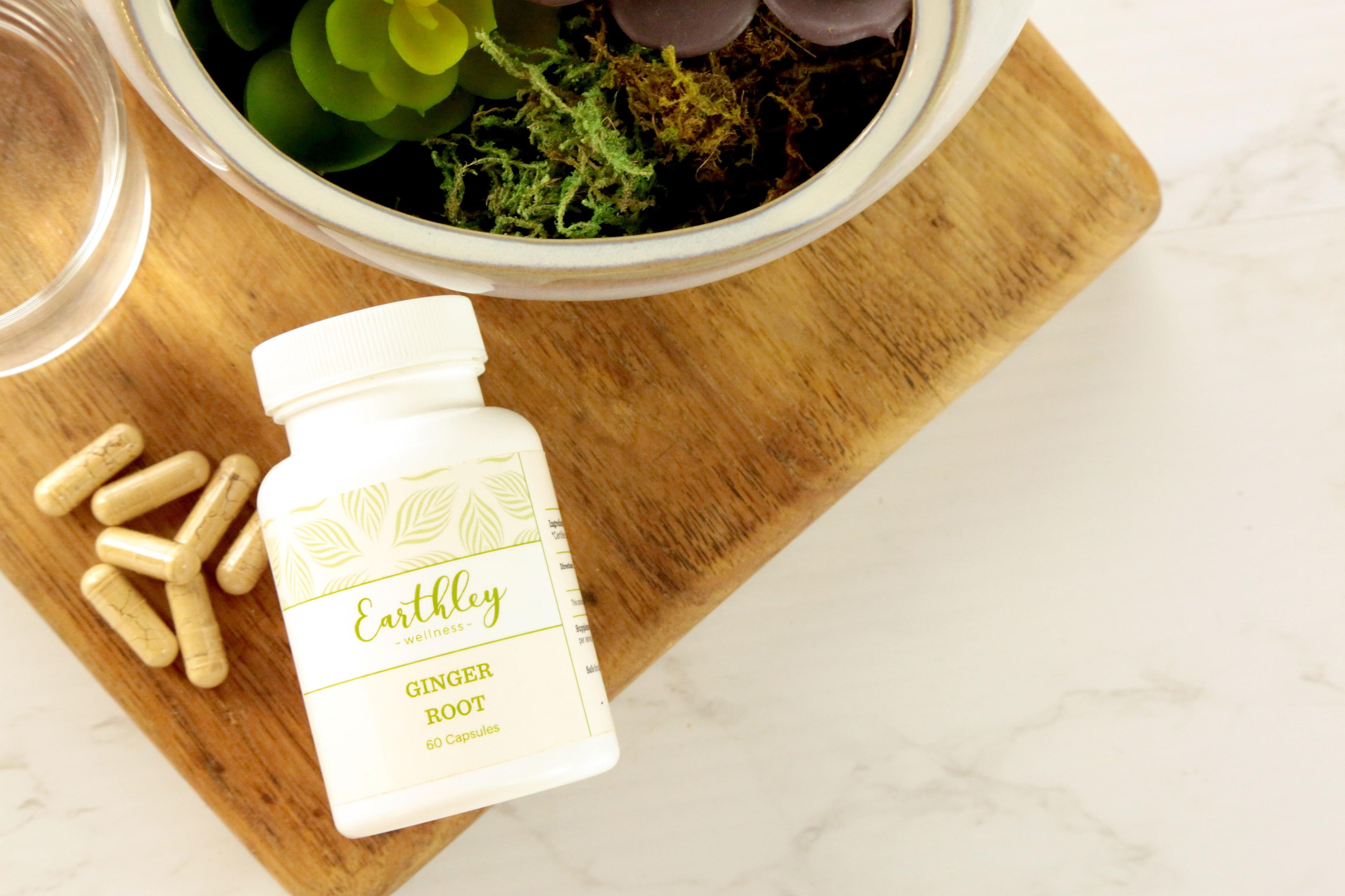 Ginger Root capsule bottle on wooden board with loose tan capsules and succulent plant