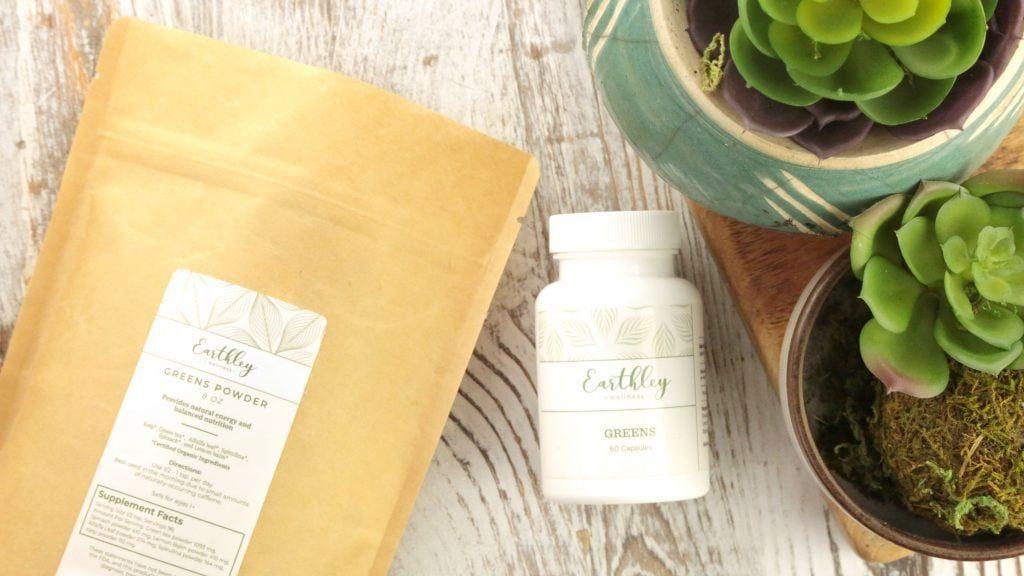 Greens Powder bag and Greens capsule bottle displayed with potted succulents
