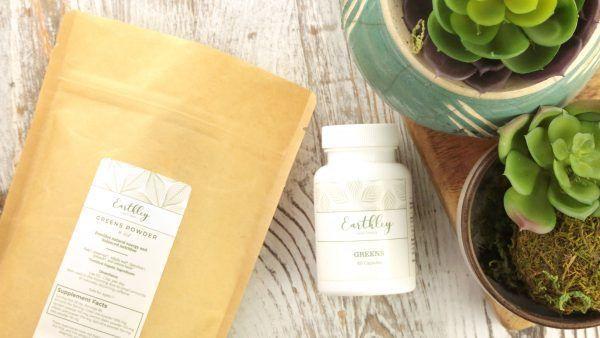 Greens Powder bag and Greens capsule bottle displayed with potted succulents
