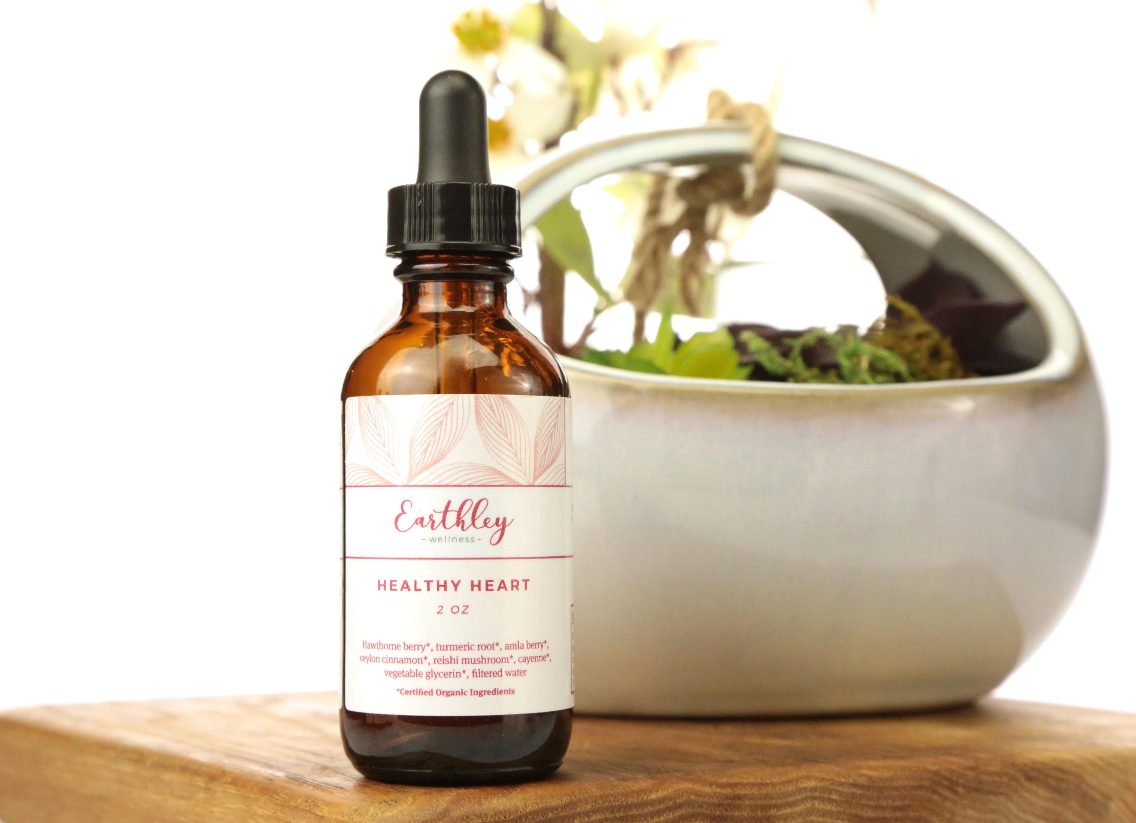 Healthy Heart 2oz herbal extract in amber dropper bottle with coral pink leaf pattern label listing hawthorne turmeric amla on wood with plant