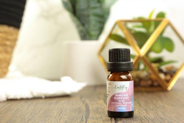 Immune Support essential oil blend in small amber bottle with pink label and plant decor