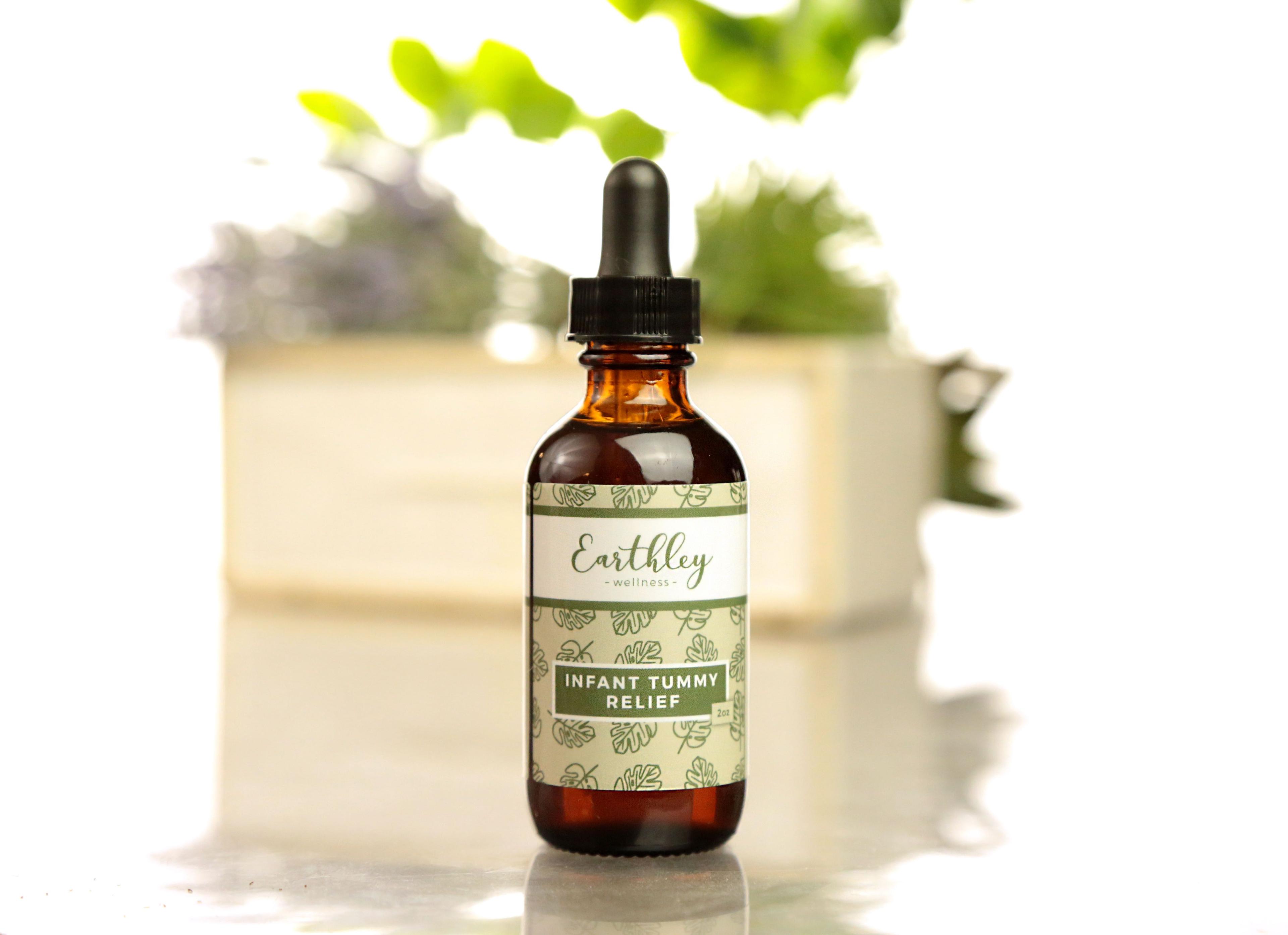 Earthley Infant Tummy Relief tincture bottle with green monstera leaf pattern label and plant in background