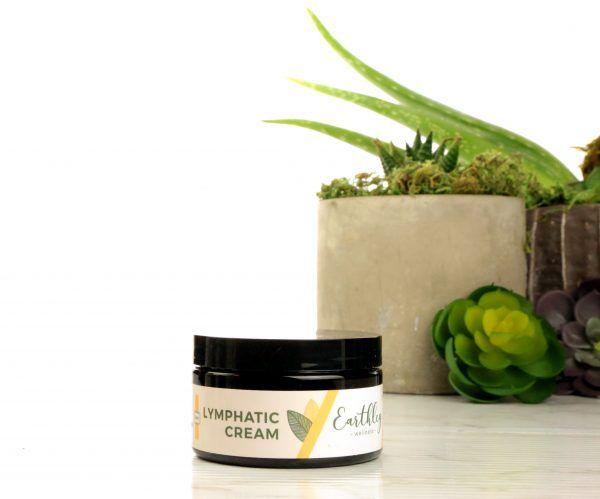 Lymphatic Cream in dark jar with yellow leaf label surrounded by succulents and aloe