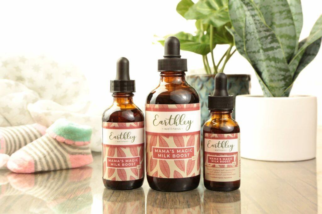 Mama's Magic Milk Boost in three sizes with pink leaf labels, baby socks visible