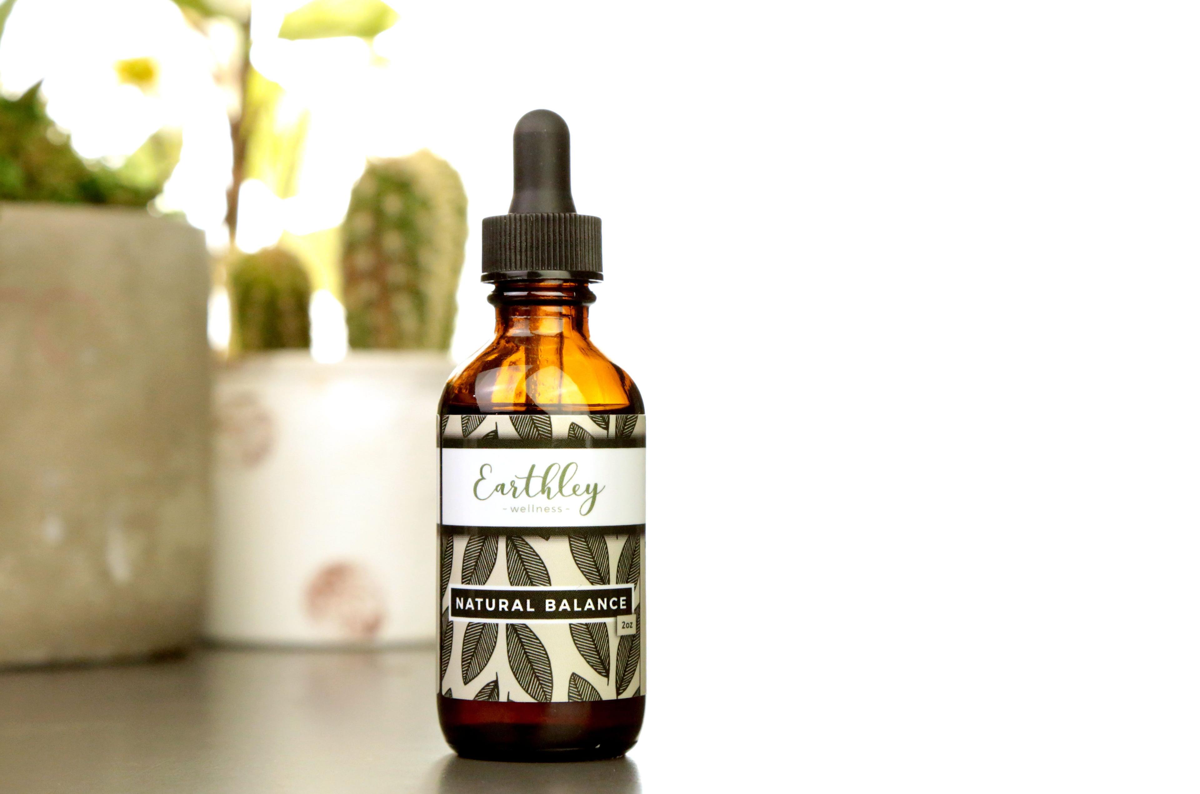 Natural Balance 2oz herbal extract in amber dropper bottle with olive green leaf pattern label, cactus and flowers in background