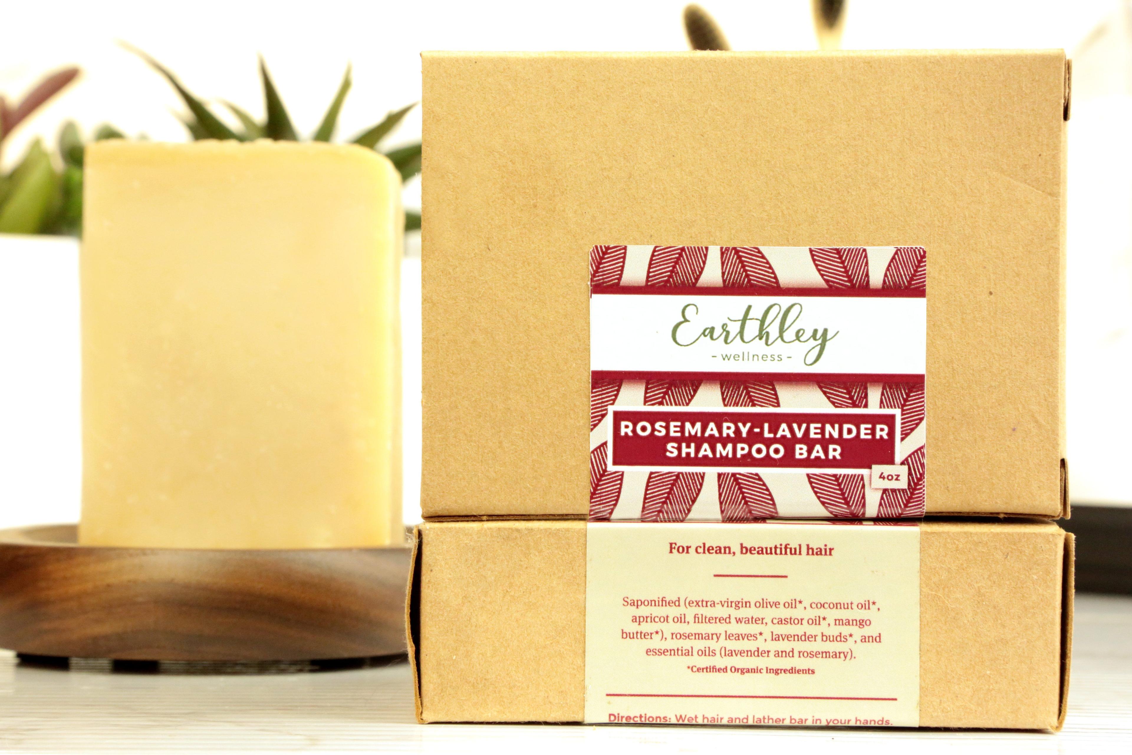 Earthley Rosemary Lavender Shampoo Bar 4oz tan kraft boxes stacked showing burgundy red leaf pattern label with golden yellow soap bar on dark brown wooden dish with green succulent plant behind