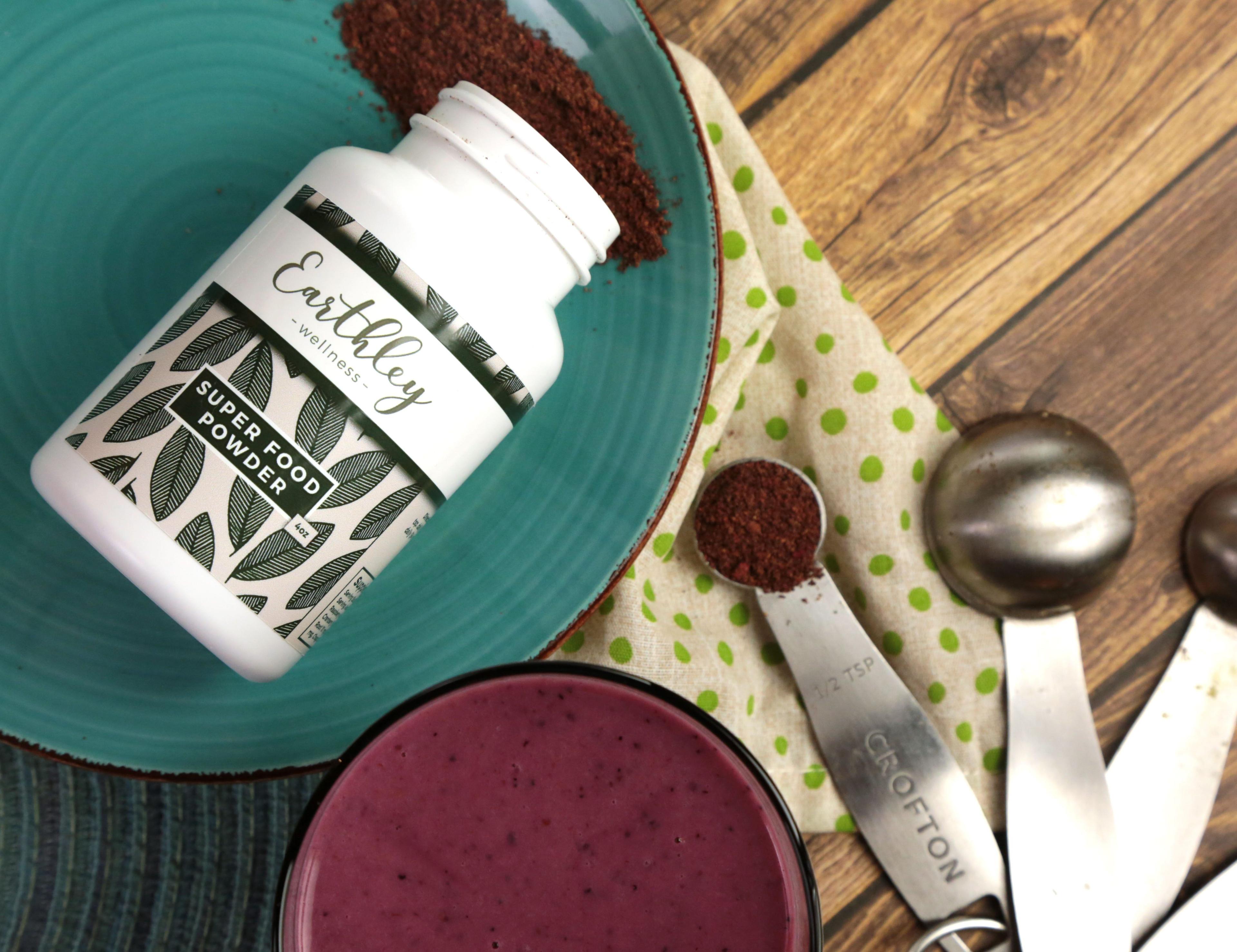 Natural Wellness Classes for Kids Week 2 supplies showing Earthley Super Food Powder bottle with purple smoothie and measuring spoons on teal plate