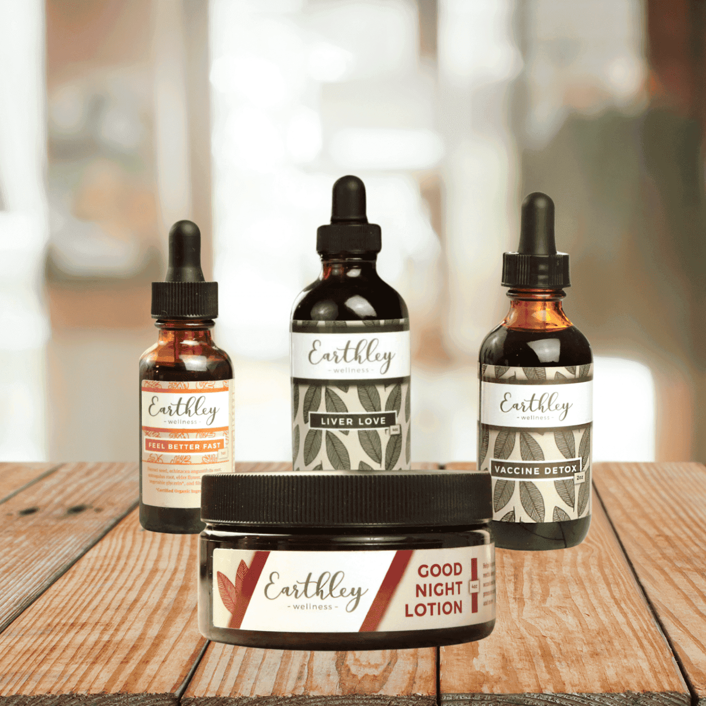 Earthley Naturopathic Bundle featuring amber glass dropper bottles with brown tan leaf labels and amber Good Night Lotion jar with black lid on wooden surface with soft background