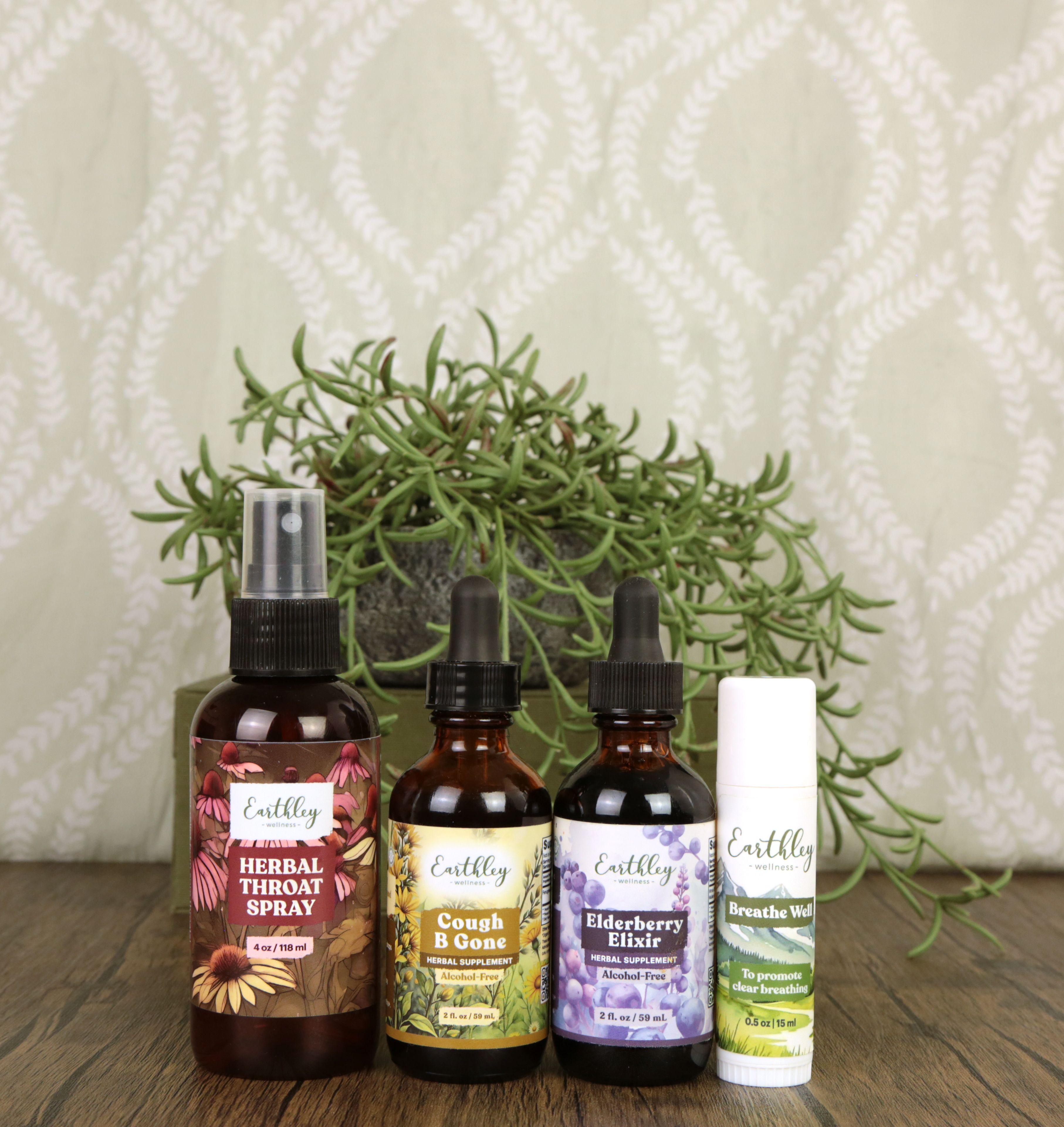 Earthley Respiratory Remedies bundle featuring Herbal Throat Spray 4 oz, Cough B Gone 2 oz Alcohol-Free tincture, Elderberry Elixir 2 oz Alcohol-Free tincture, and Breathe Well 0.5 oz stick arranged on wooden surface with succulent plant in background