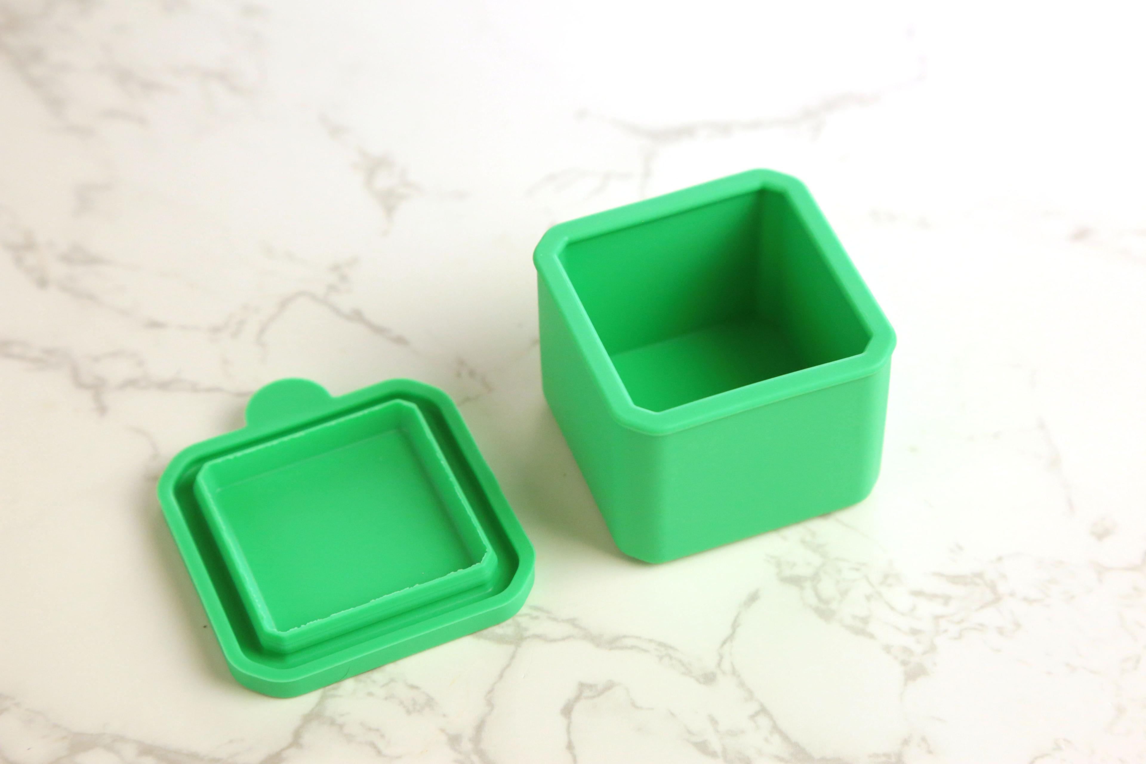 Earthley stainless steel sauce cups with lids removed showing interior portion size for dips and dressings on marble surface