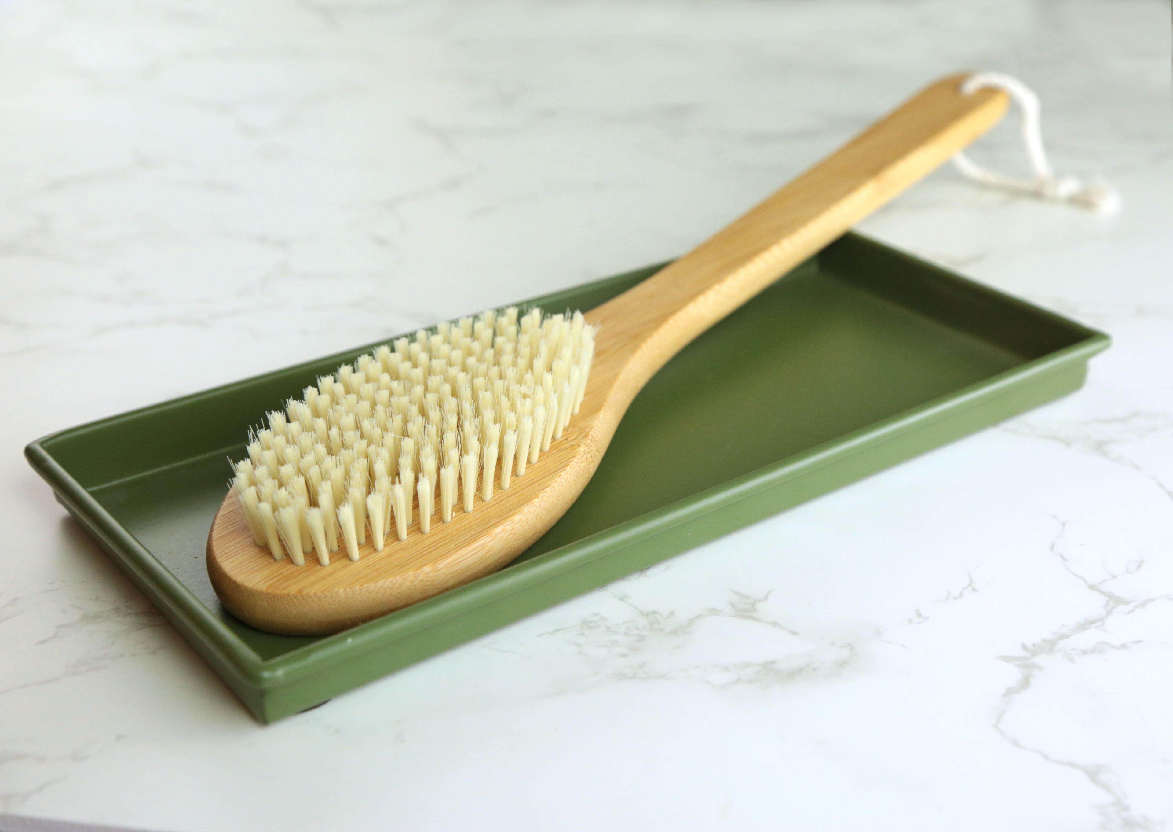 Earthley dry body brush close-up showing natural sisal bristles and ergonomic wooden handle design on marble surface