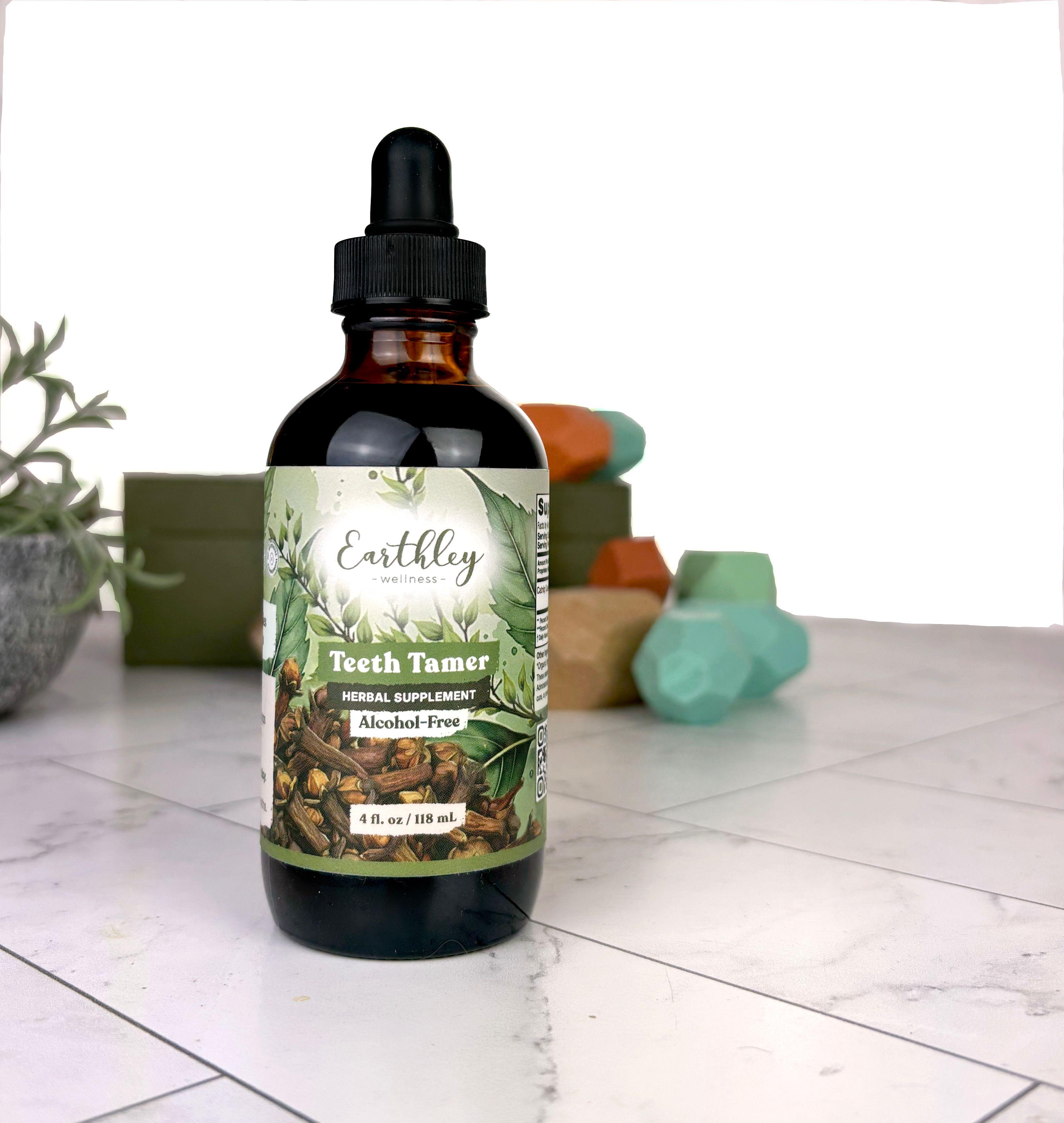 Earthley Teeth Tamer herbal supplement bottle with dropper on marble surface with colorful soap bars in background