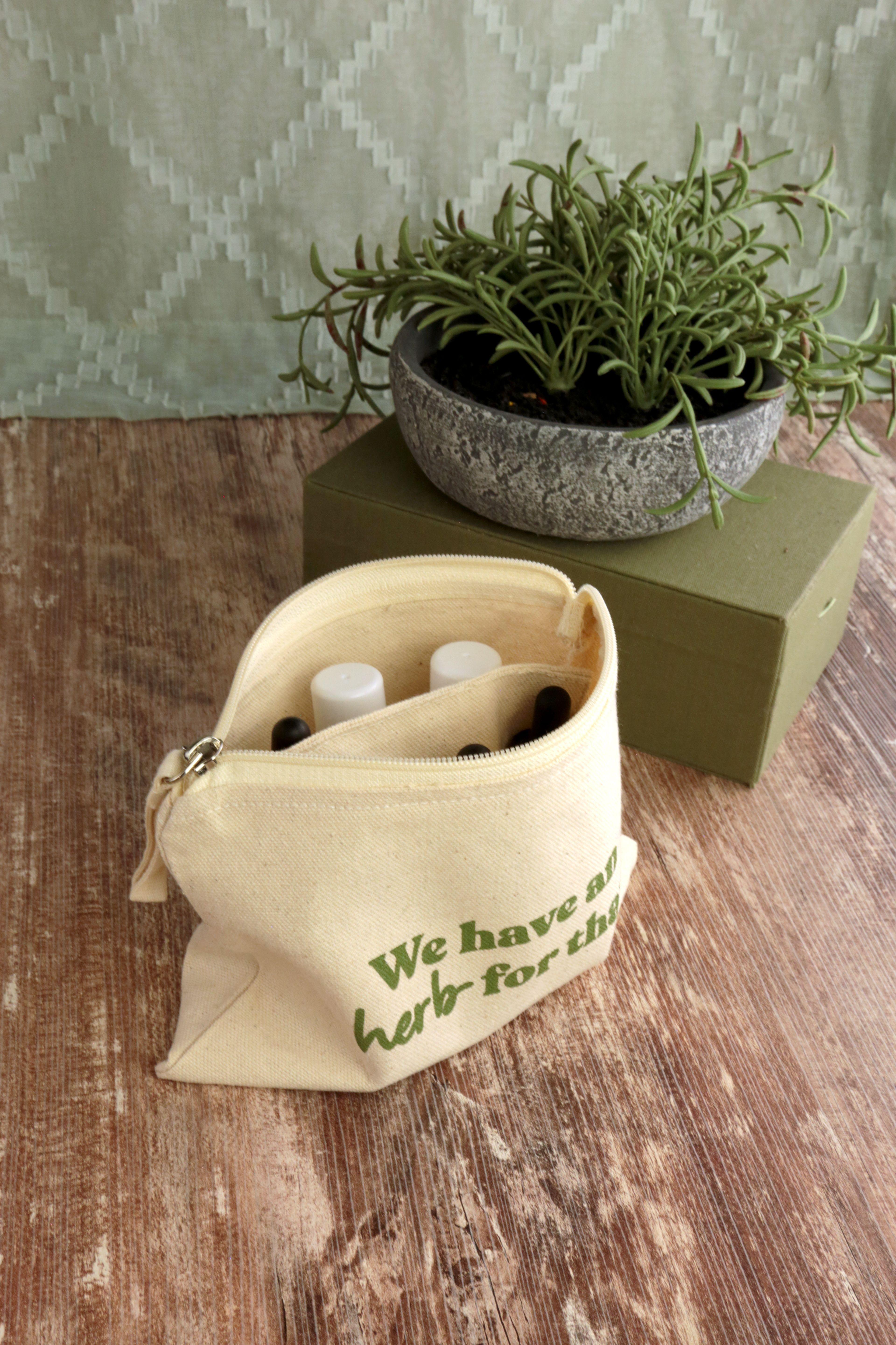 Earthley Tincture Carrying Bag product photo showing natural canvas pouch with herb for that text and gold zipper on rustic surface