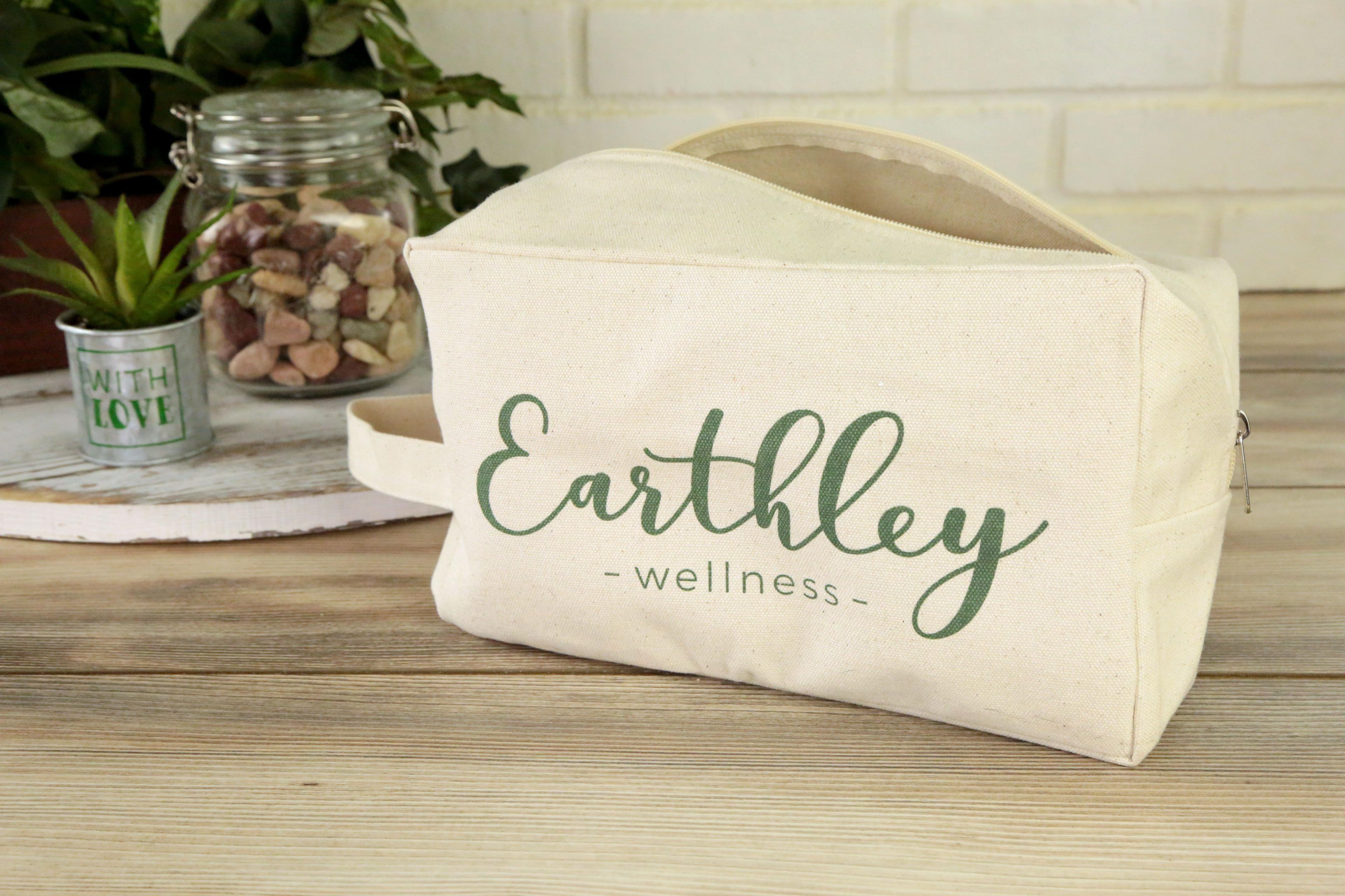 Natural canvas travel toiletry bag with Earthley Wellness logo in green script